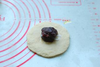 取出一个小面团，擀开成圆片，包上一颗豆沙馅，15克左右就够了，不要太多，否则后期不仅整形困难，还会影响面包的美观。