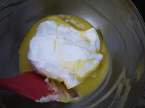 把3分之1的蛋白霜加入到蛋黄糊中，用刮刀混合均匀。
