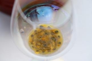 将百香果汁和百香果仔放入红酒杯内。