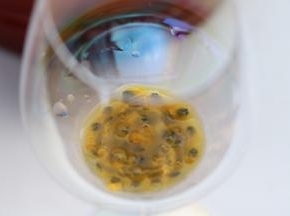 将百香果汁和百香果仔放入红酒杯内。