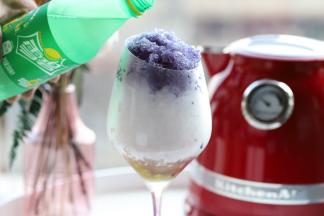 往红酒杯上缓慢的倒入雪碧。