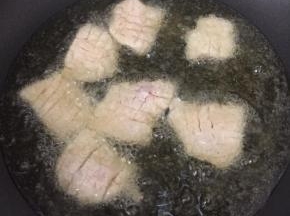 油烧至八成热时放入肉片，炸至金黄色。