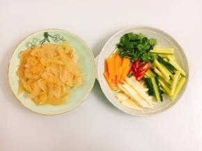 海蜇头沥干水分，用刀切成薄片，胡萝卜、青瓜、香菜、子姜、小米辣切成小段备用
