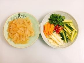 海蜇头沥干水分，用刀切成薄片，胡萝卜、青瓜、香菜、子姜、小米辣切成小段备用
