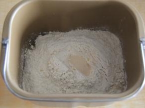 放入多谷物面包粉，粉上挖洞，放入酵母。