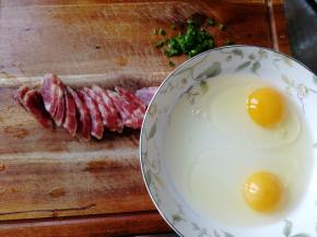 葱洗净，切成葱花。腊肠拿水冲洗一下，斜刀切成薄片，15片。鸡蛋清洗一下，如果外表有点脏的话。磕入碗里。