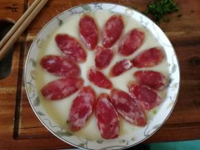 然后取出。用盘夹取出，转移到砧板上，排入切好的腊肠片。已经初步蒸凝固，不会沉下去滴！放心放！