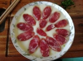 然后取出。用盘夹取出，转移到砧板上，排入切好的腊肠片。已经初步蒸凝固，不会沉下去滴！放心放！