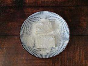 盘里倒入一点淀粉，豆腐片两面都沾上薄薄一层的淀粉。
