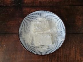 盘里倒入一点淀粉，豆腐片两面都沾上薄薄一层的淀粉。