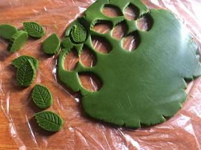 再将抹茶粉面团擀成同样薄片，并用树叶模具刻出树叶面片；