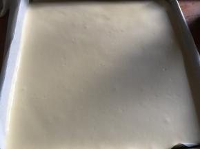 在距离烤盘15厘米高度将蛋糕糊均匀倒入事先垫好油布（油纸、硅胶垫）的烤盘内，用刮板把蛋糕糊表面抹平，再轻震烤盘，震出大气泡；