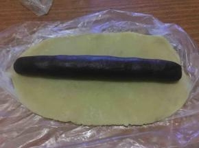 将大的那份原味面团擀成薄片，再将可可粉面团滚圆成薄片长度，放置其上；
