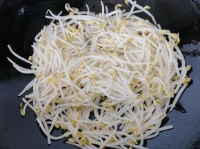 锅里倒入少许的油，因为绿豆芽不吃油，再加上我们做的是减肥营养菜，所以油少放一些，放入葱花和蒜片炝锅，倒入焯好水的绿豆芽翻炒一下。