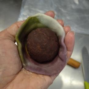 把擀好的面皮再整理完美一点，用掌心托住面皮，切面在下，把馅料放在正中心。