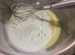 搅拌好的蛋黄液盆中筛入低筋面粉，用打蛋器搅拌至润滑的状态；