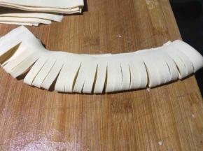 取出一小张对折，然后用刀均匀的切成3毫米宽的小细条，对折其边处不要切断，留出4毫米的宽度；