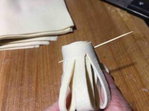 然后左手按住细条，右手大拇指和食指将对折齐边从下往上卷起来；