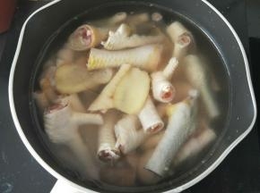 锅里放适量水，然后倒入鸡爪，再放入姜片，中火烧开后加入料酒，煮8分钟。