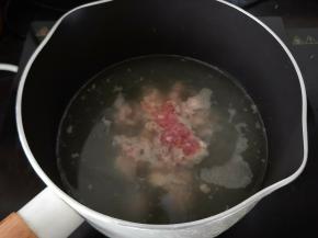 锅里放适量水或是高汤，因为南瓜花比较少，我大概就放了两碗水的量，烧开后倒入适量食用油。然后倒入腌好的猪肉，用筷子搅散开。