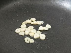 不粘锅放少许食用油，然后放入蒜片，小火煎至两面焦黄，盛出放入大米锅里。