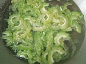 苦瓜清洗干净切成两半，挖去里面的籽和白瓤，然后切成薄片；锅里放入清水，再加入一丢丢盐和少许食用油，烧开后倒入苦瓜焯水一分钟，捞出控一下水分。