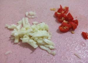 李子拍好后，再把蒜头和辣椒都切碎，辣椒和蒜头切得越碎越好。