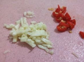 李子拍好后，再把蒜头和辣椒都切碎，辣椒和蒜头切得越碎越好。
