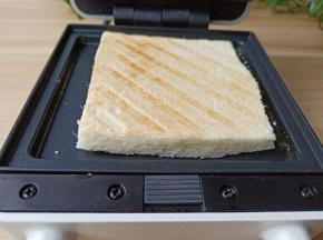 两片吐司切去边沿，放三明治机烤两面金黄。