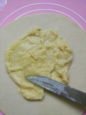 醒发后，把面团擀成圆形。饼皮上抹一层榴莲肉