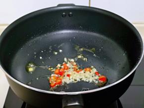 不粘锅中加入切好的蒜末和辣椒，小火煸炒出香味。