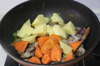 加入土豆块、胡萝卜块翻炒。