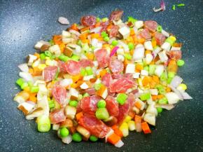 热锅热油，加入洋葱爆香，加火腿炒至透明色，依次加入香菇、豌豆、玉米、香干、胡萝卜、芹菜翻炒均匀。