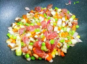 热锅热油，加入洋葱爆香，加火腿炒至透明色，依次加入香菇、豌豆、玉米、香干、胡萝卜、芹菜翻炒均匀。