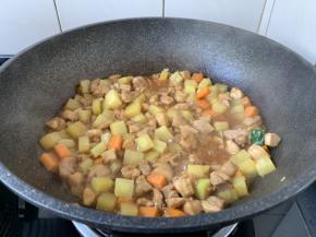 放入胡萝卜和土豆，翻炒均匀，倒入2小碗的水，炖煮5分钟左右。