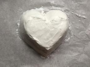 烤盘铺上油纸，用刮刀将打好的蛋清堆成爱心的形状。