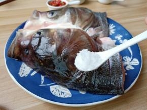 在鱼头内部和外部都切上花刀，便于去腥入味，加盐一勺里外抹均匀。