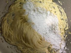 把糖粉分2次加入到黄油中，每次都把糖粉充分混合，高速打发蓬松。然后再加第二次的糖粉打发。打发好的黄油颜色发白，体积蓬松。