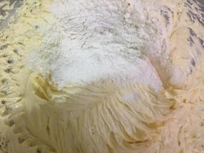把过筛的面粉和柠檬汁分3次加到黄油糊中，用电动打蛋器搅拌均匀。