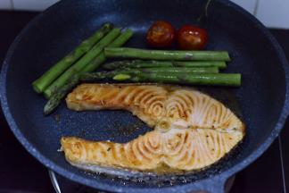 一面金黄后翻面再煎，并放入芦笋和圣女果，一起煎熟。