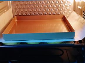 发酵好的喜饼胚是原来两倍大，盖上一张油纸，再放上一个烤盘。