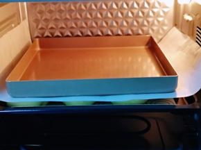 发酵好的喜饼胚是原来两倍大，盖上一张油纸，再放上一个烤盘。