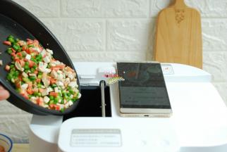 打开饭来APP，机器会有一个预热的过程。预热完成后，会有提示投放第一步的食材。把刚才我们用食用油拌好的各种蔬菜丁投进锅里，投料完成，自动翻炒。