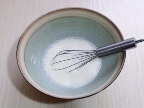 将牛奶倒入器具中，用手动打蛋器打散。