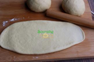 取一个醒发好的小面团，用擀面杖擀成长条状面皮，宽度要和自己的土司模具宽度一致或稍微小一点