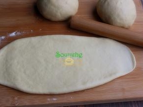 取一个醒发好的小面团，用擀面杖擀成长条状面皮，宽度要和自己的土司模具宽度一致或稍微小一点