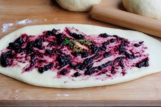 擀开的面团上面均匀涂抹一层蓝莓果酱，