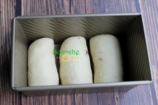 吐司模具四周涂抹一层黄油，把卷好的面团，收口朝下，放入土司盒底部。