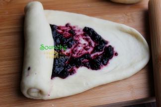 涂好蓝莓果酱的面皮，由上至下卷起来，一直卷到头，成为圆柱形的面团。