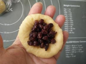 取一个面团擀圆，翻面放入适量红豆馅。